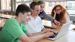 Vier Jugendliche schauen auf einen Laptopbildschirm.